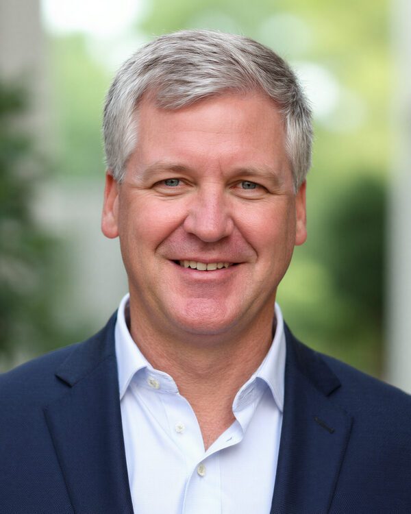 George Macon professional man with gray hair smiling in an atrium wearing a blue blazer