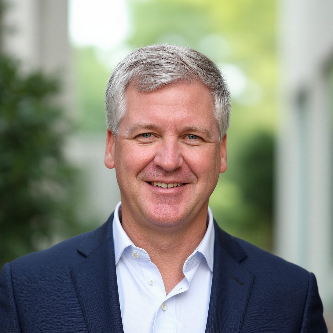 George Macon professional man with gray hair smiling in an atrium wearing a blue blazer