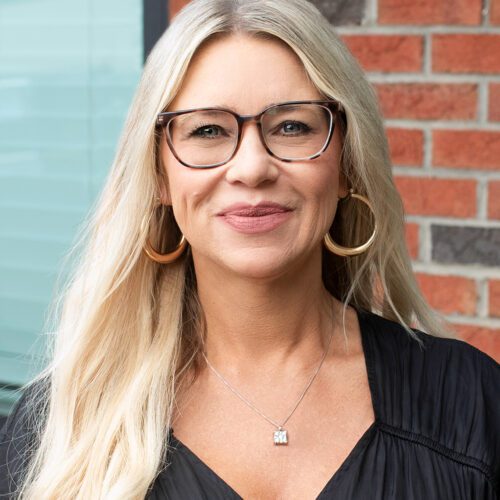 Lea Myers blond woman smiling outside with long blonde hair and a black blouse