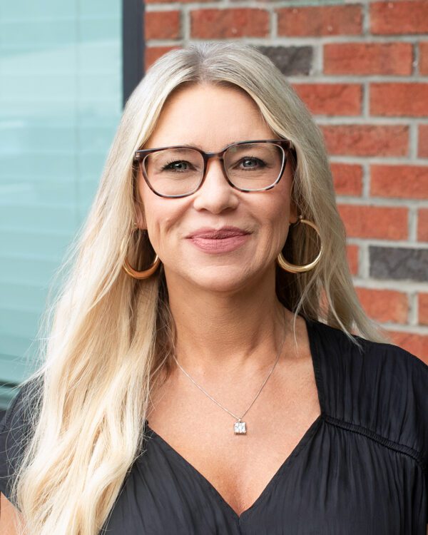 Lea Myers blond woman smiling outside with long blonde hair and a black blouse