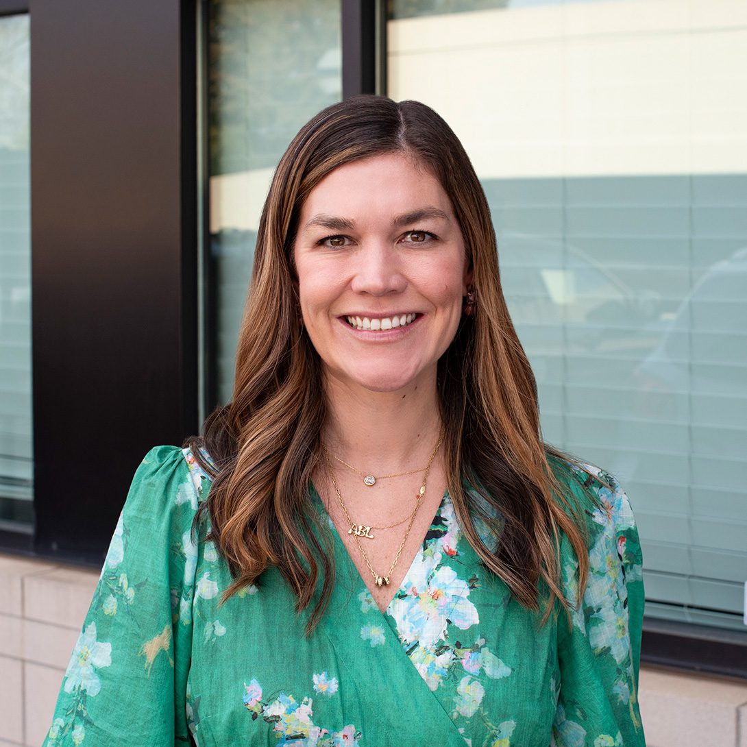 Robbie (Branstrom) Adams woman with a green dress and long brown hair smiling