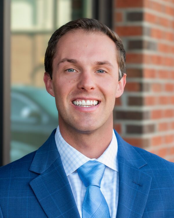 young main in a blue suit and tie smiling outside