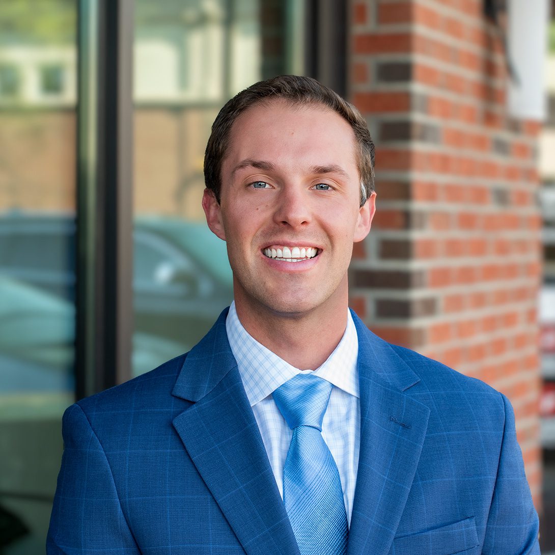 young main in a blue suit and tie smiling outside