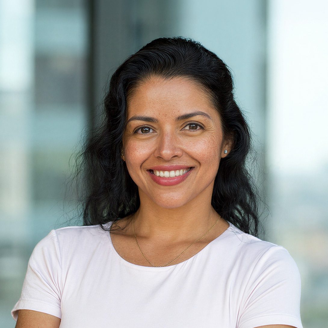 woman smiling standing inside with dark hair and white shirt