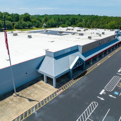 exterior of 1-story retail building with white roof on a sunny day in Concord, NC