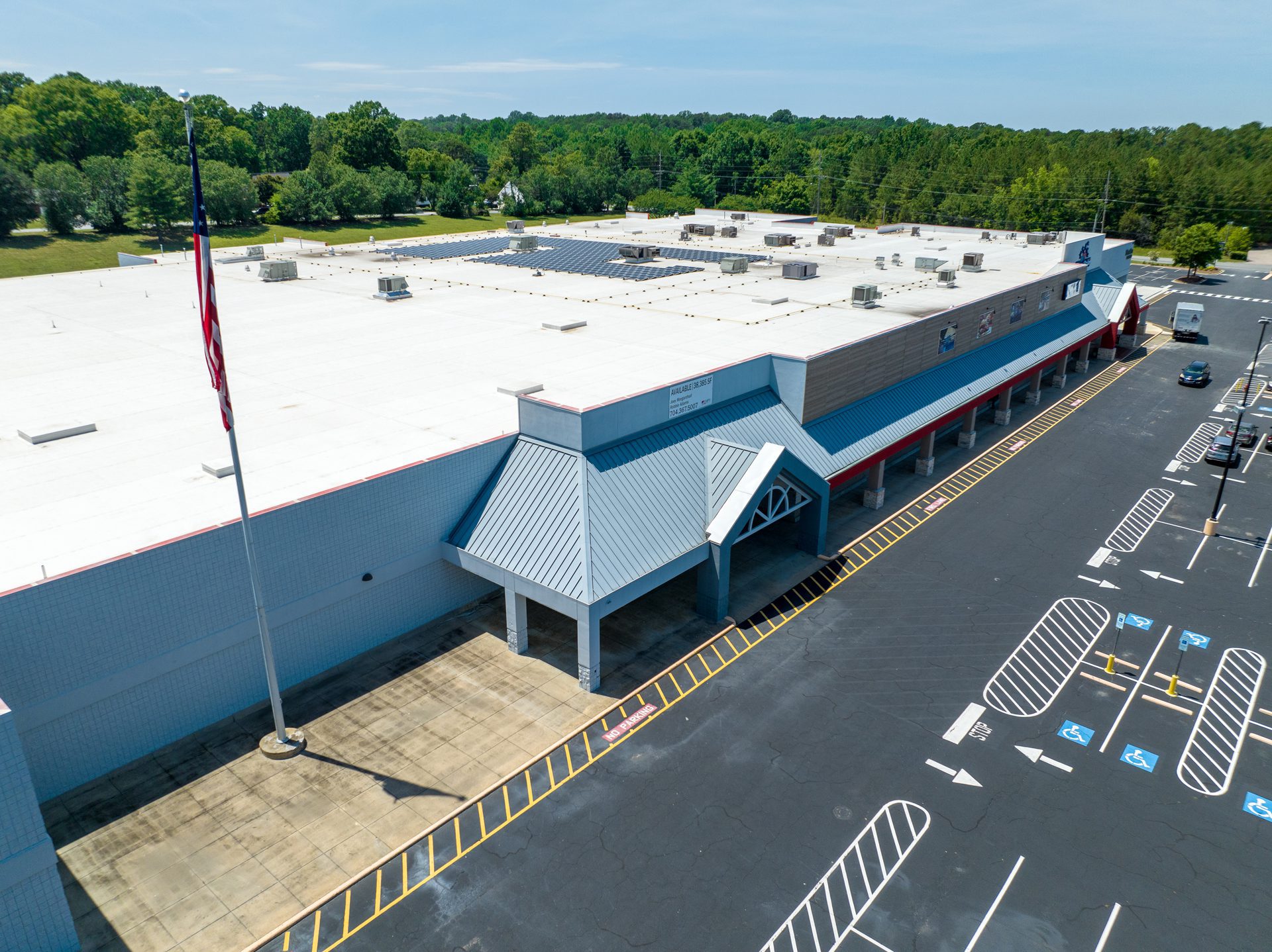 exterior of 1-story retail building with white roof on a sunny day in Concord, NC