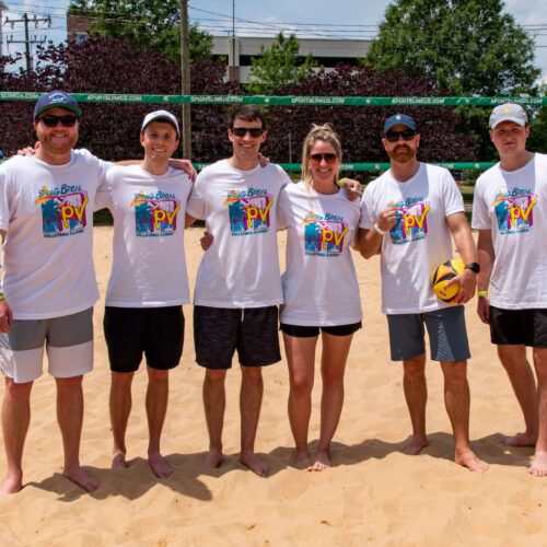 MPV volleyball team six players in white MTV styled shirts on sand volleyball court