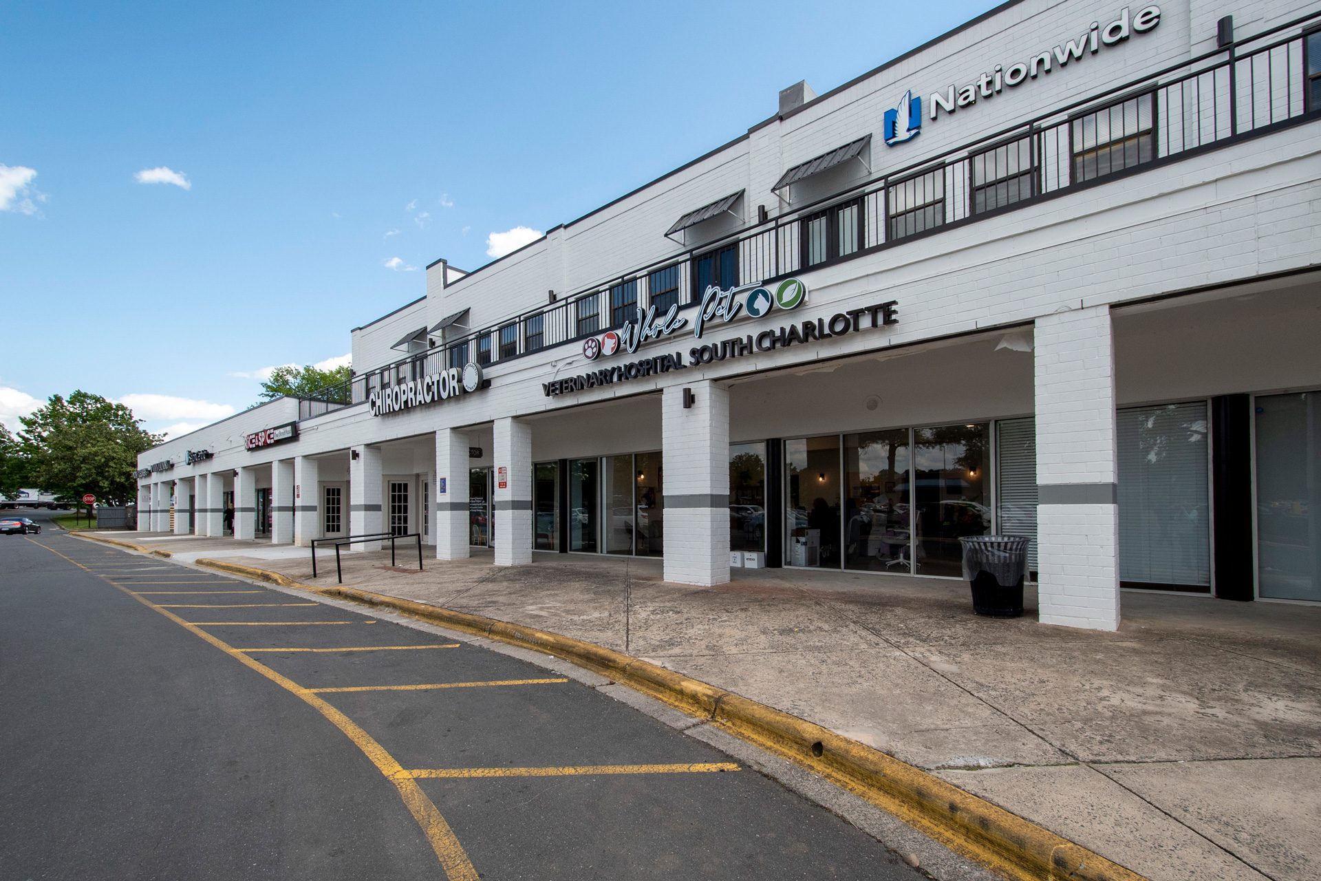 Whole Pet Veterinary Hospital exterior entrance a white brick 2-story retail building