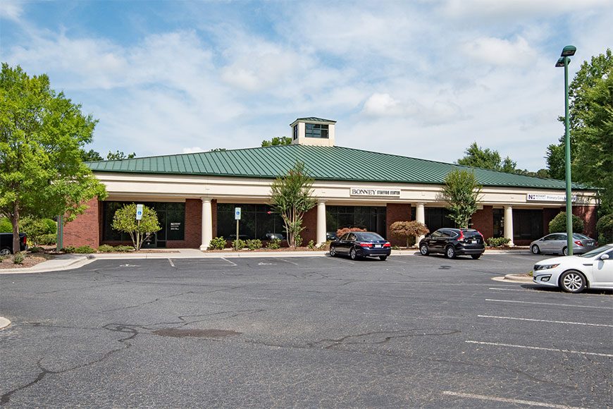 Outside of Medical Office Brick Building with green roof and cars in front
