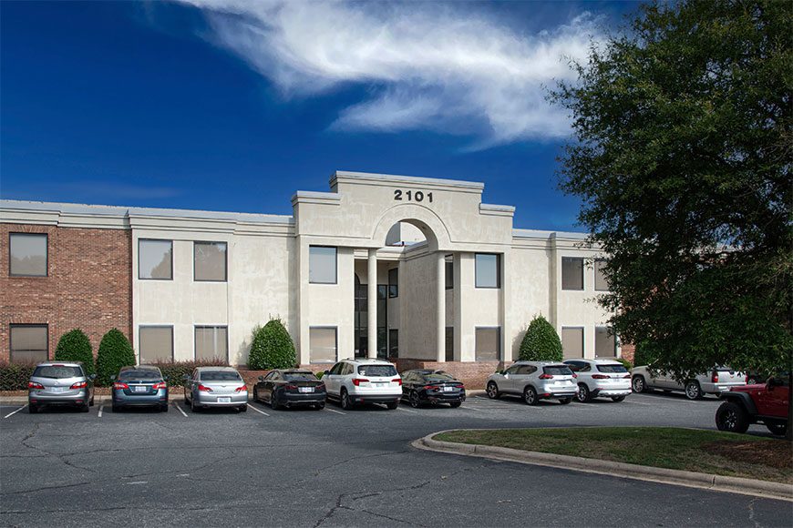 White 2 Story Office Building with Columns and parking lot in front