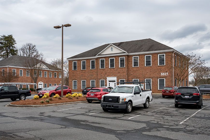 Brick Two Story Office Building with Parking lot and cars in front