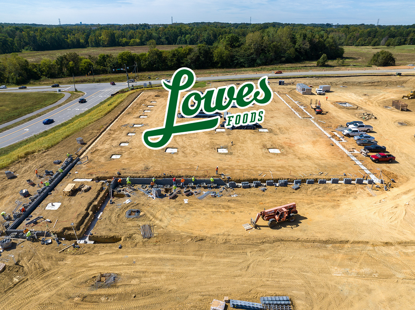 pad site for Lowes Foods with logo superimposed on dirt outlined by building foundation beginnings