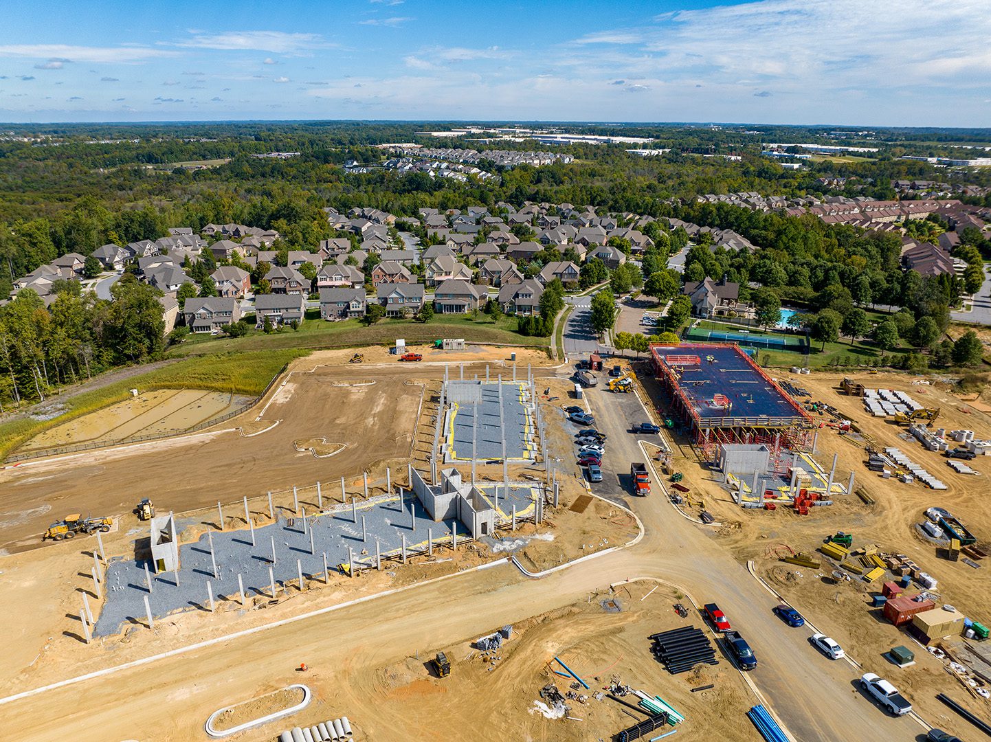 aerial image of construction at Christenbury Village with 3 building pads progressing and residential in background