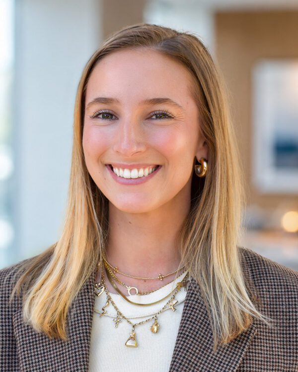 Morgan Luca young woman smiling inside an office in a tweed jacket