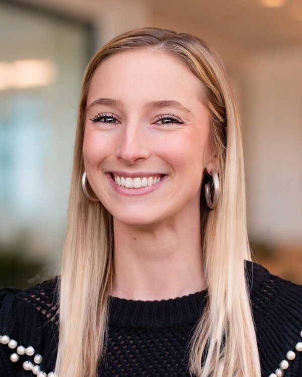 Morgan Lucas young blonde woman smiling in an office setting in a black sweater
