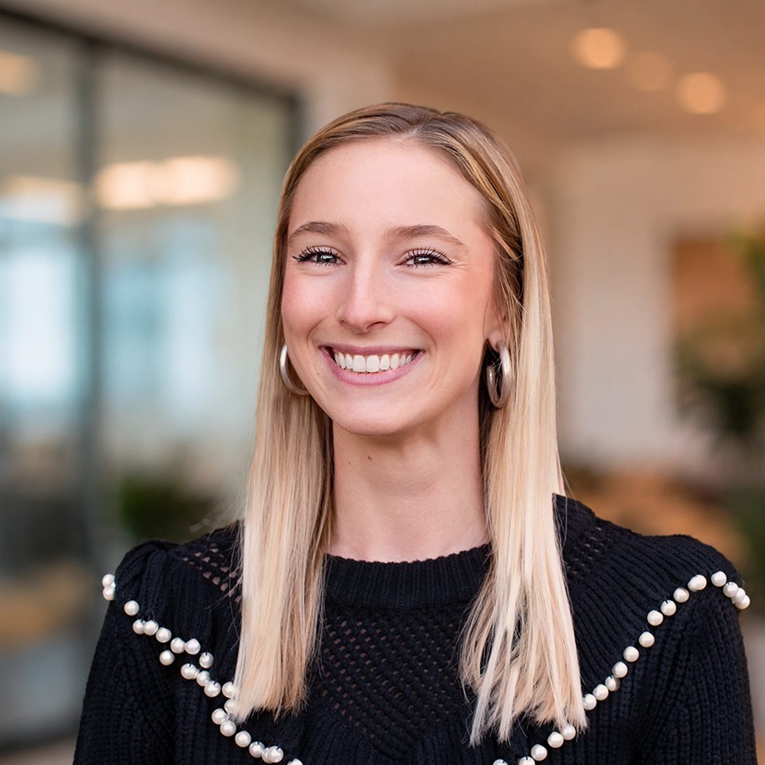 Morgan Lucas young blonde woman smiling in an office setting in a black sweater