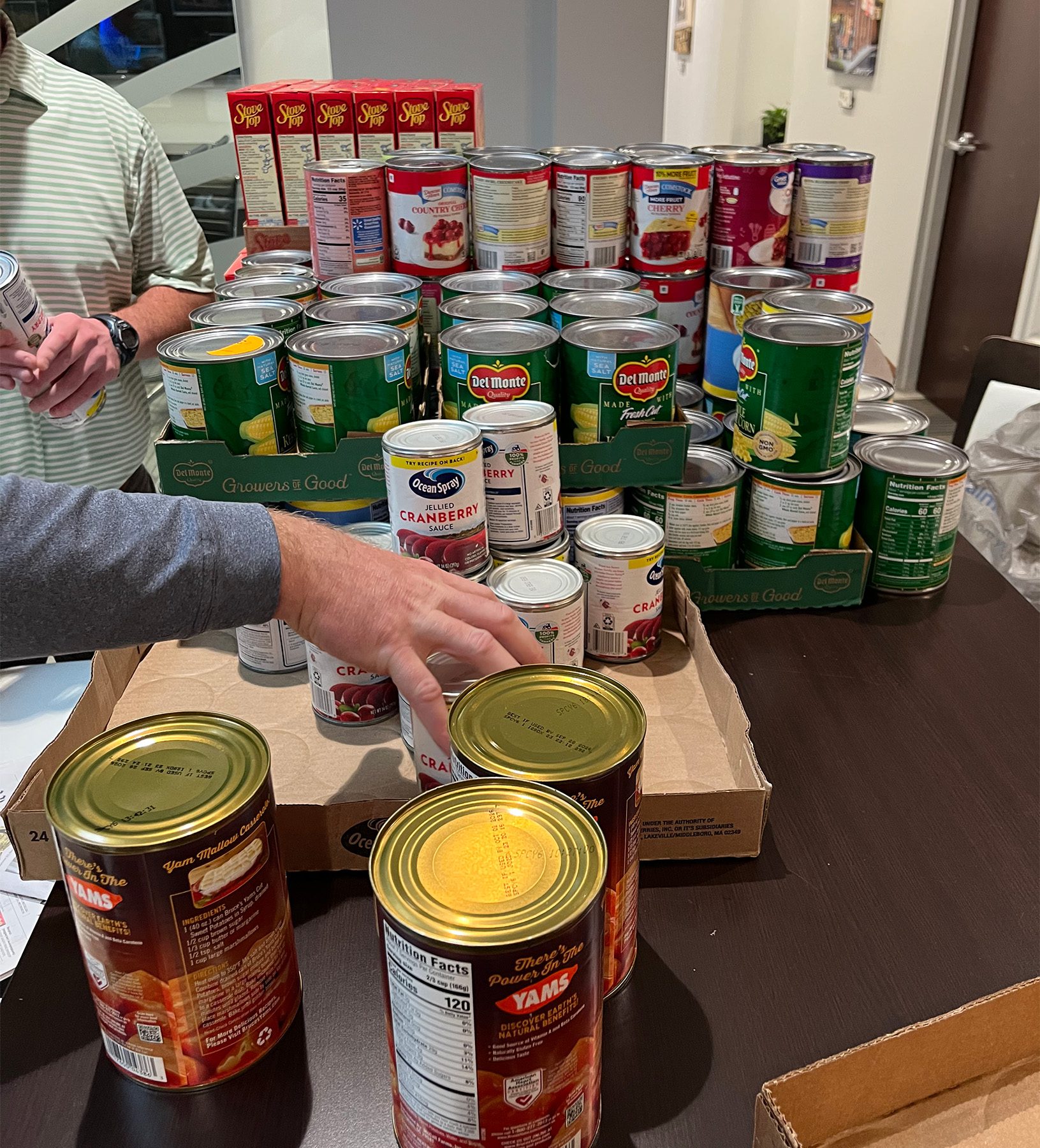 hand reaching for canned food on a table
