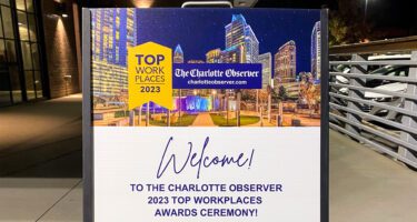 Top Workplaces outdoor event sign presented by The Charlotte Observer in the evening