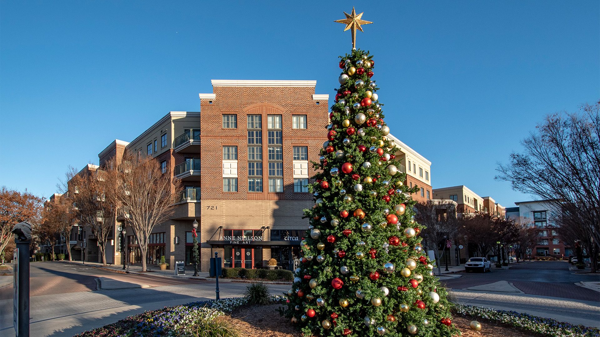 4-story brick building with retail on bottom and residential on top and a Christmas tree in foreground in the early morning