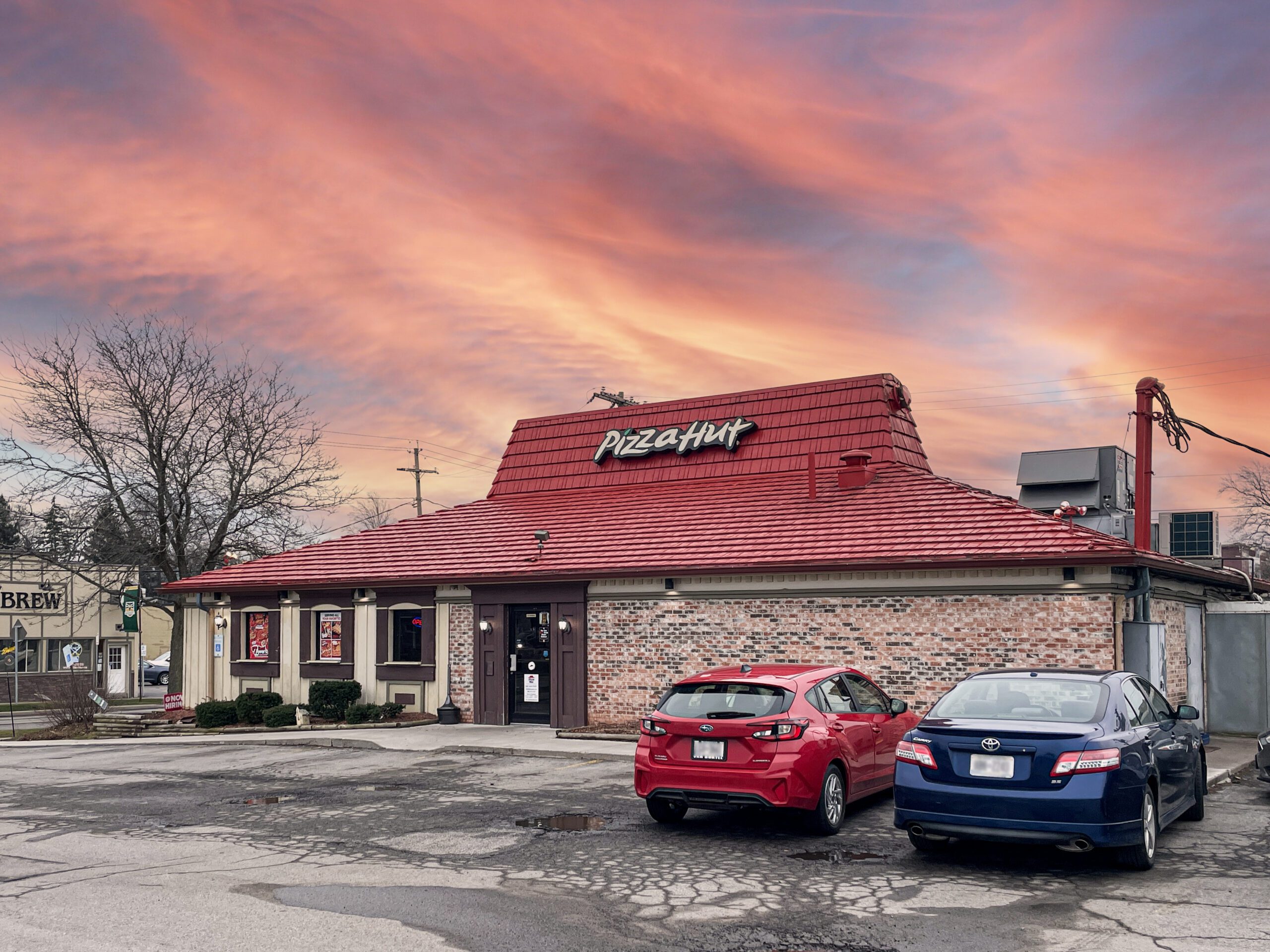 Brick Pizza Hut with cars in front