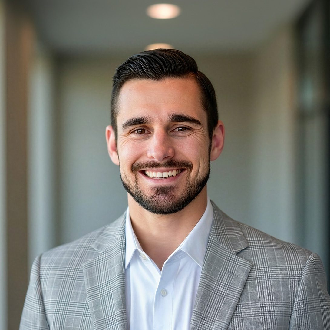 Chad Pyke, man with dark features in a gray plaid suit inside office environment