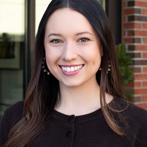 Meredith Choate young woman with brunette hair smiling in front of a brick building