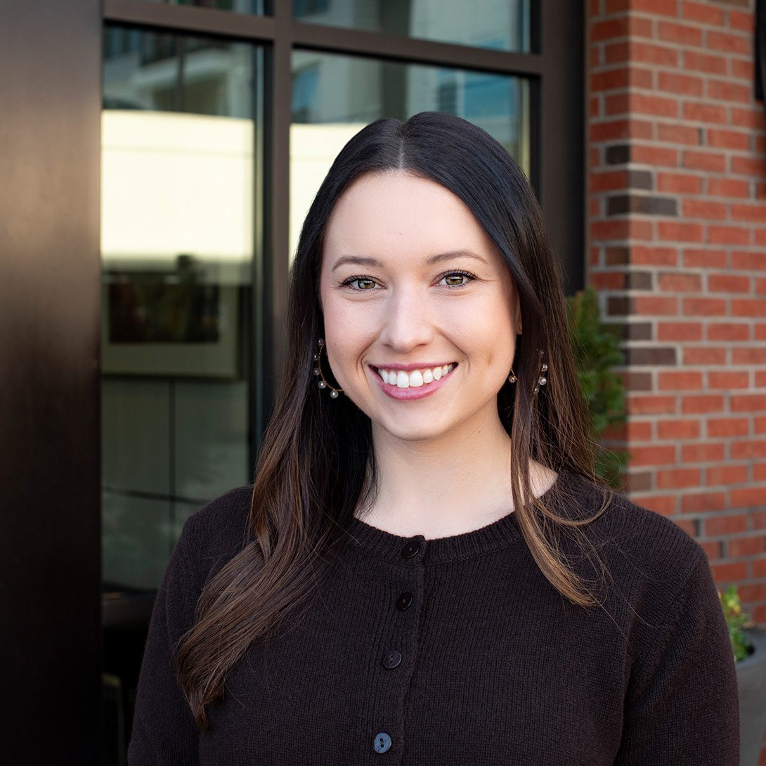 Meredith Choate young woman with brunette hair smiling in front of a brick building