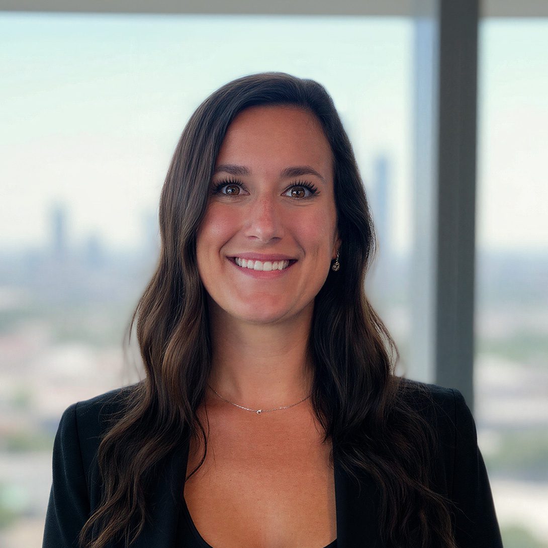 Sarah Sipe lease administrator young woman with long brown hair inside an office building in a black blazer